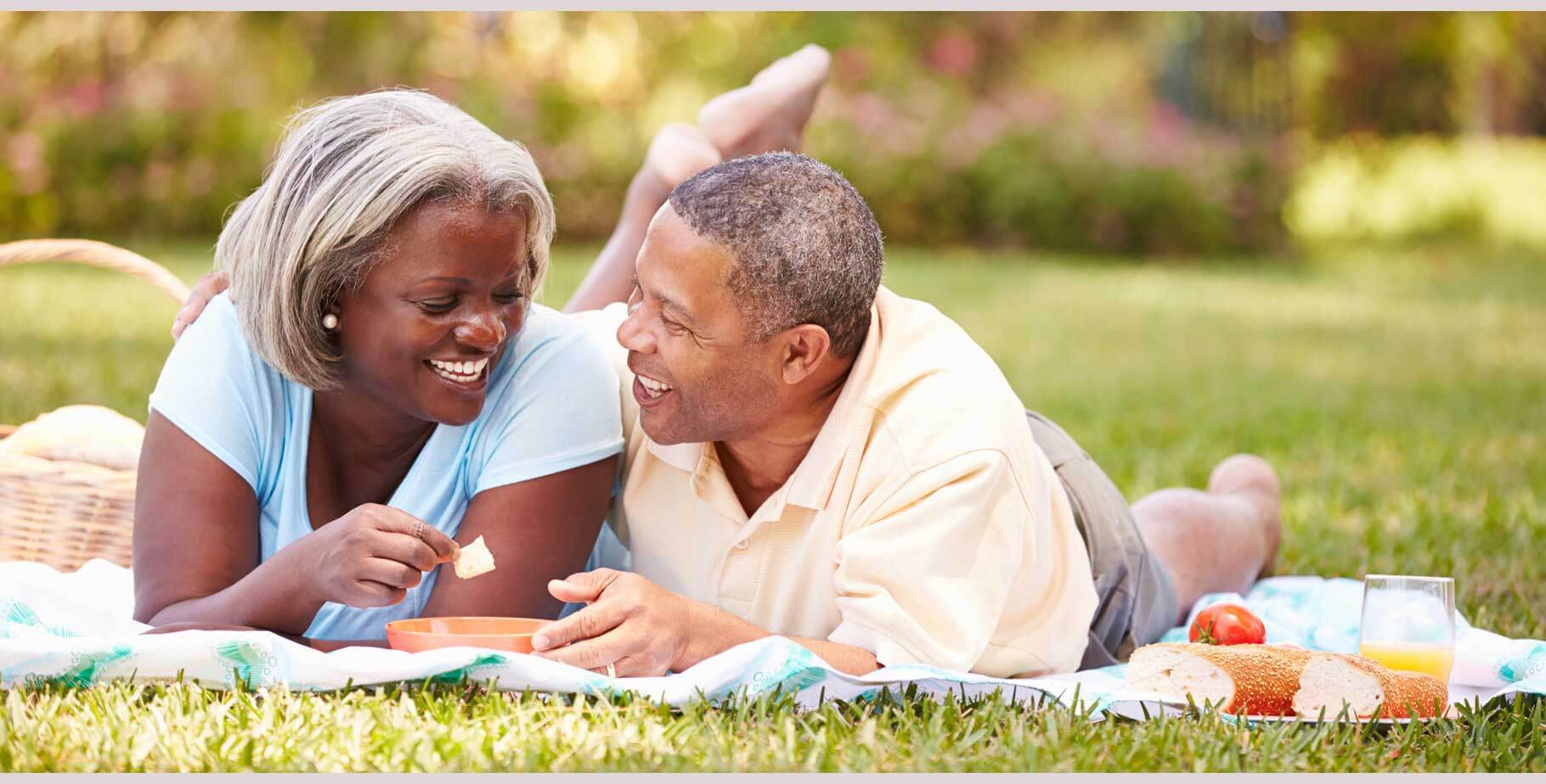 senior black couple on a blanket on grass