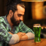 onely man drinking green beer at bar or pub