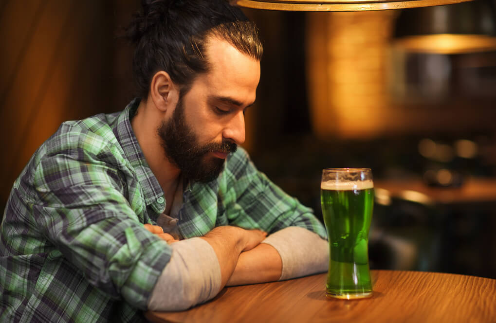 lonely man drinking green beer at bar or pub