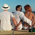 Woman talking boyfriend while holding hands another man picnic sea shore