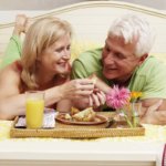 senior white couple eating in bed