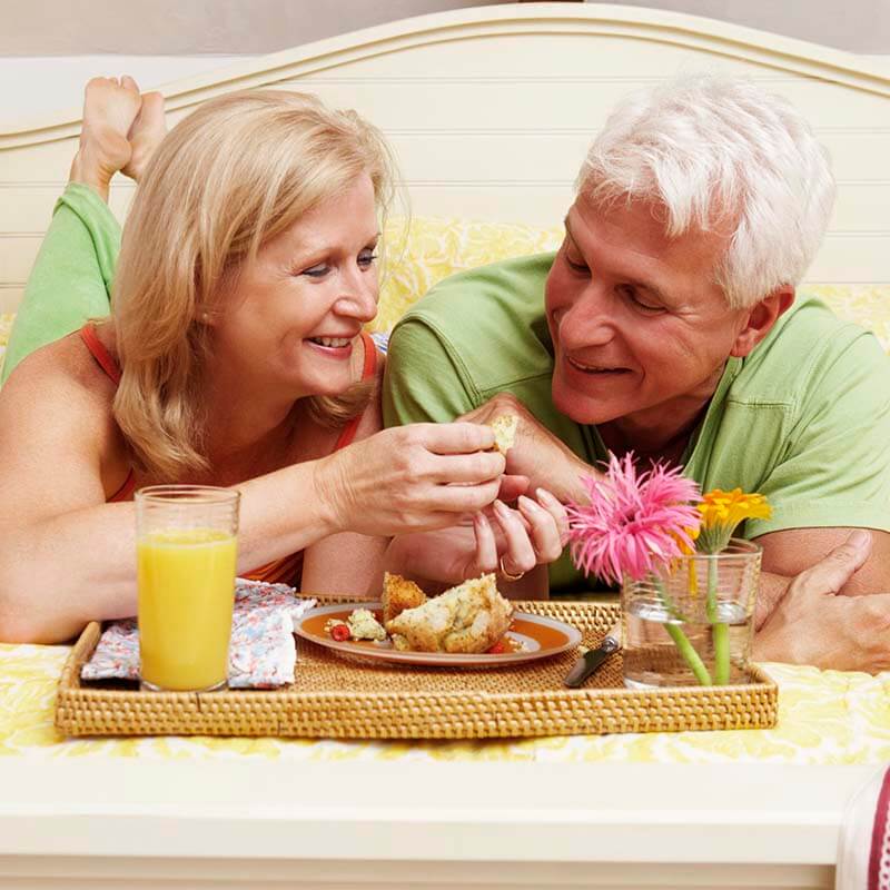 senior white couple eating in bed