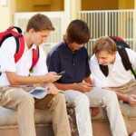 Male High School Students Using Mobile Phones On School Campus