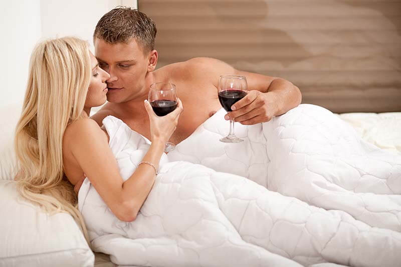 Couple drinking on the bed in bedroom