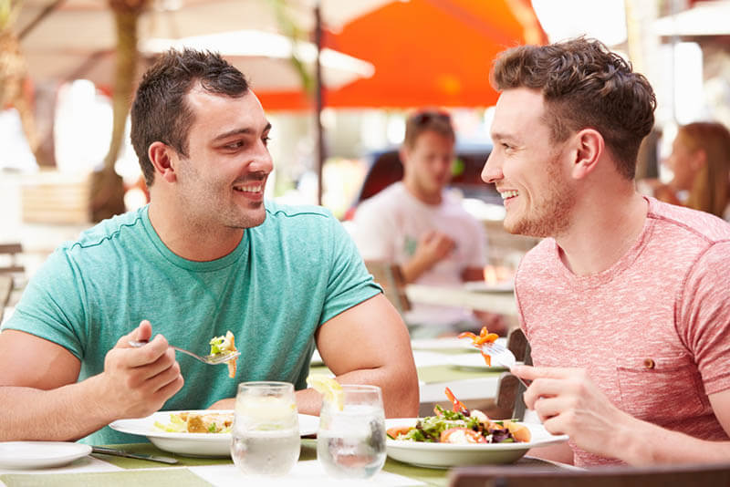 Male Couple Enjoying Lunch In Outdoor Restaurant