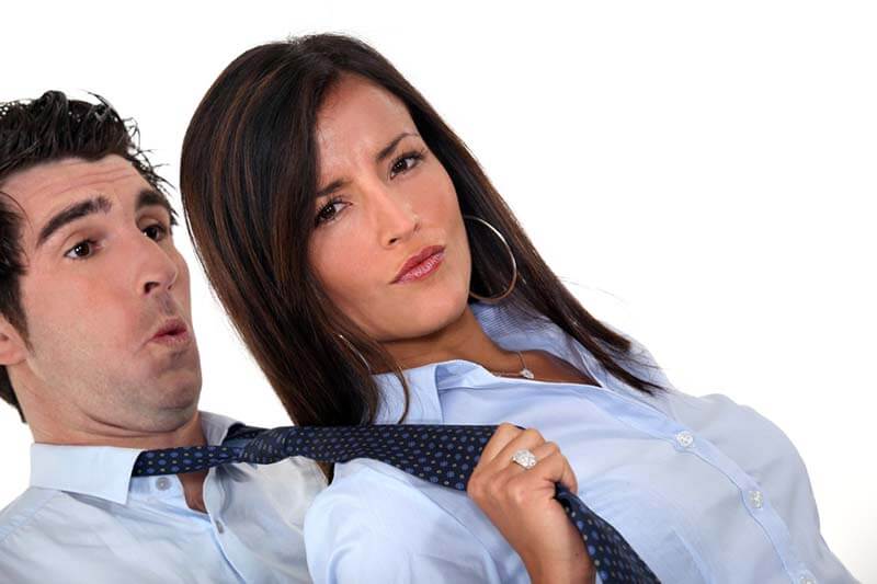 Woman pulling submissive man's tie